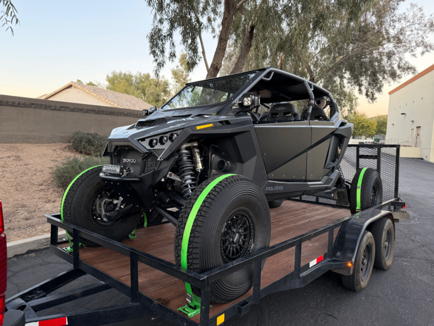 Polaris side-by-side strapped down on the wooden trailer deck.
