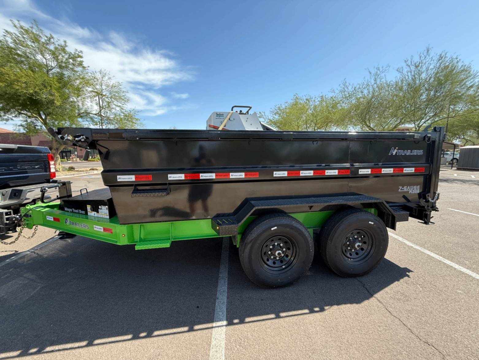 Black dump trailer with a green chassis, side profile.